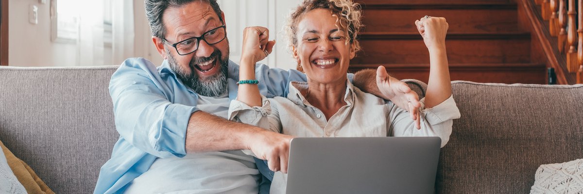 Couple excited, celebrating, while looking at laptop.