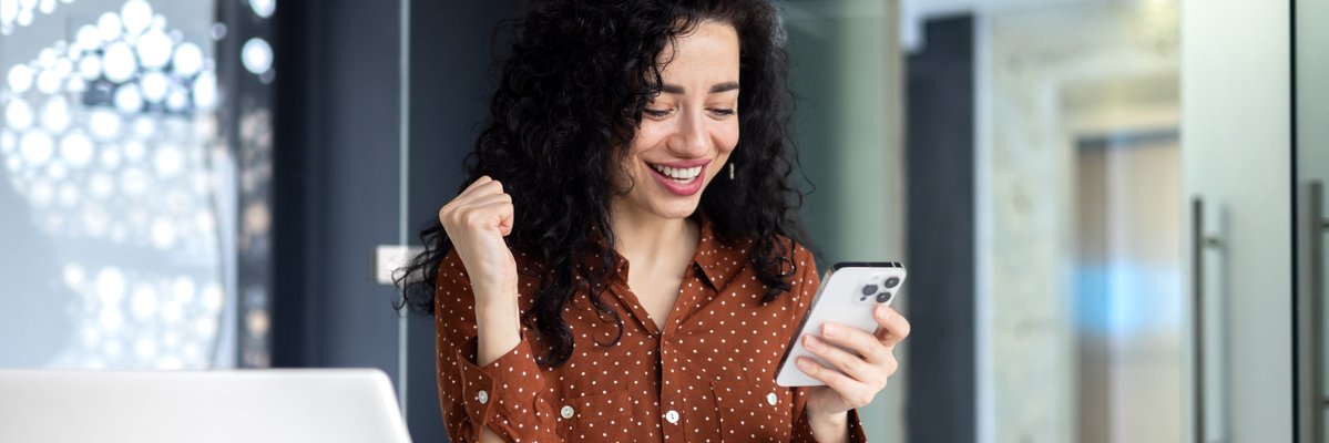 Woman with laptop and phone quietly celebrating
