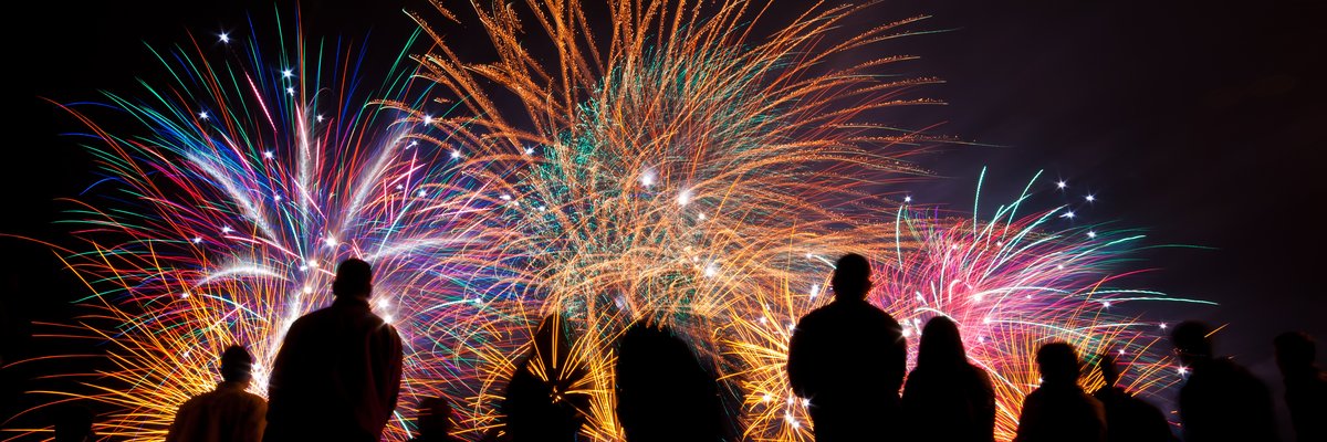 A crowd watches a colorful fireworks display.