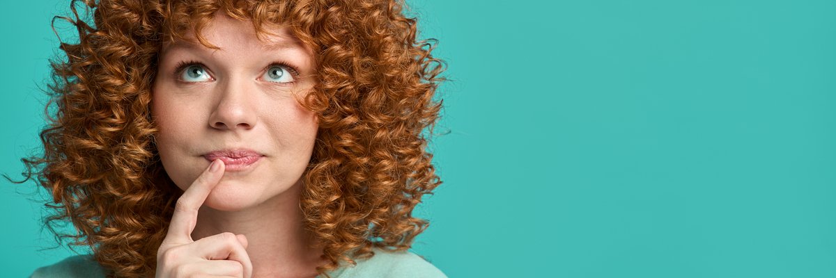 Woman holding finger to her mouth in thought.