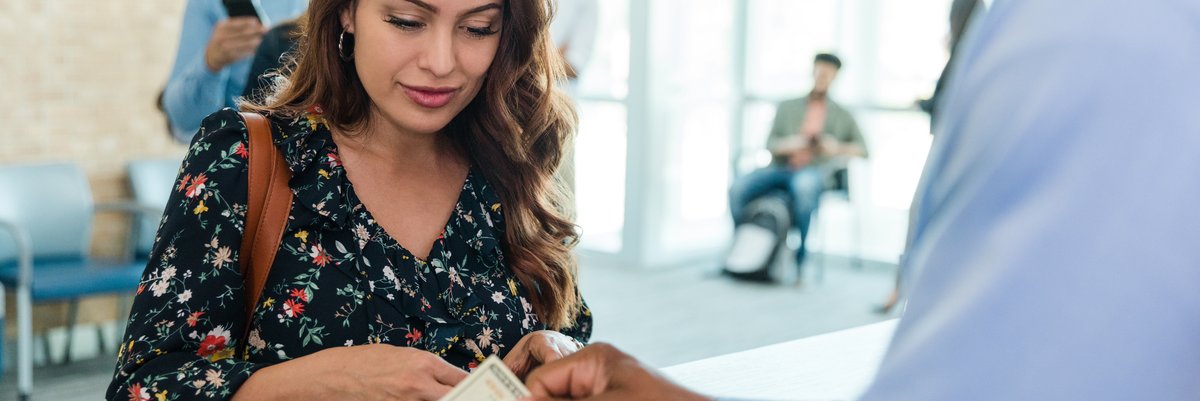 Bank customer dealing with cash with teller.