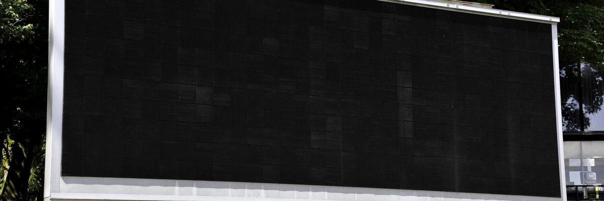 A blank scoreboard in the middle of some foliage.