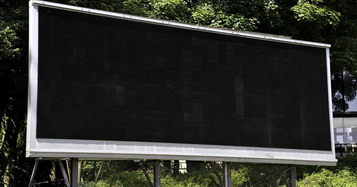 A blank scoreboard in the middle of some foliage.