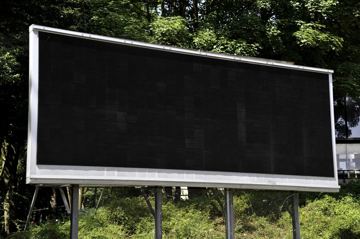 A blank scoreboard in the middle of some foliage.