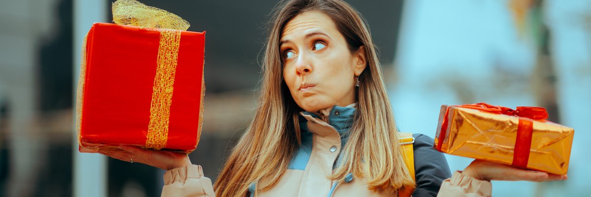 Person making skeptical face while holding gift-wrapped boxes in each hand.