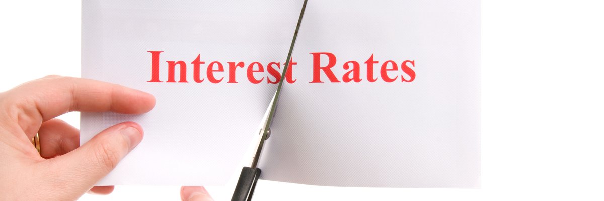 Paper that reads "Interest Rates" being cut in half by scissors.