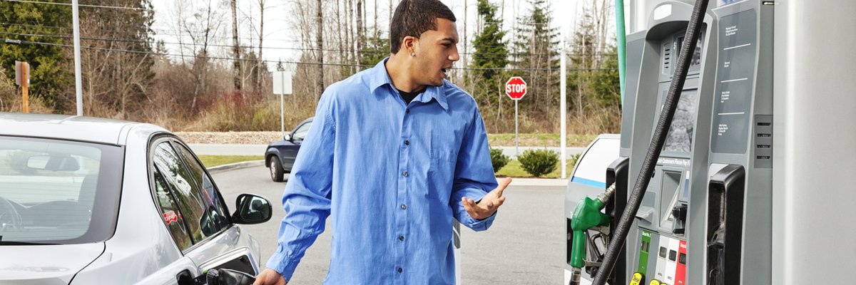 A driver fills their car's gas tank, frustrated at the rising price.