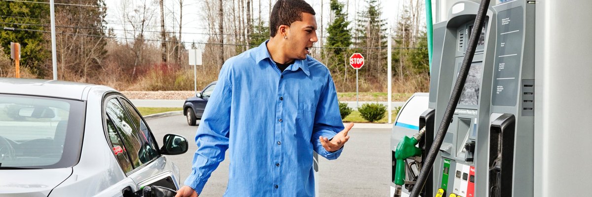 A driver fills their car's gas tank, frustrated at the rising price.