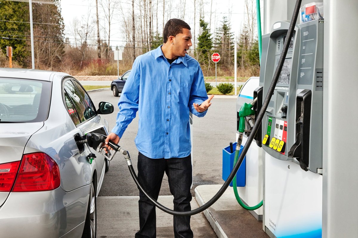 A driver fills their car's gas tank, frustrated at the rising price.