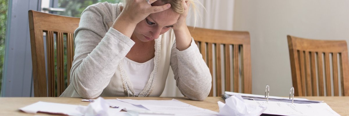 Frustrated woman with head in hands sitting at table
