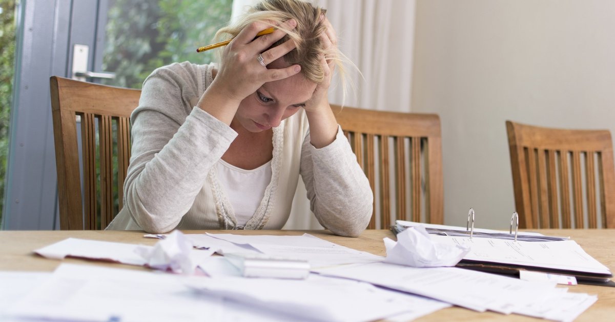 Frustrated woman with head in hands sitting at table