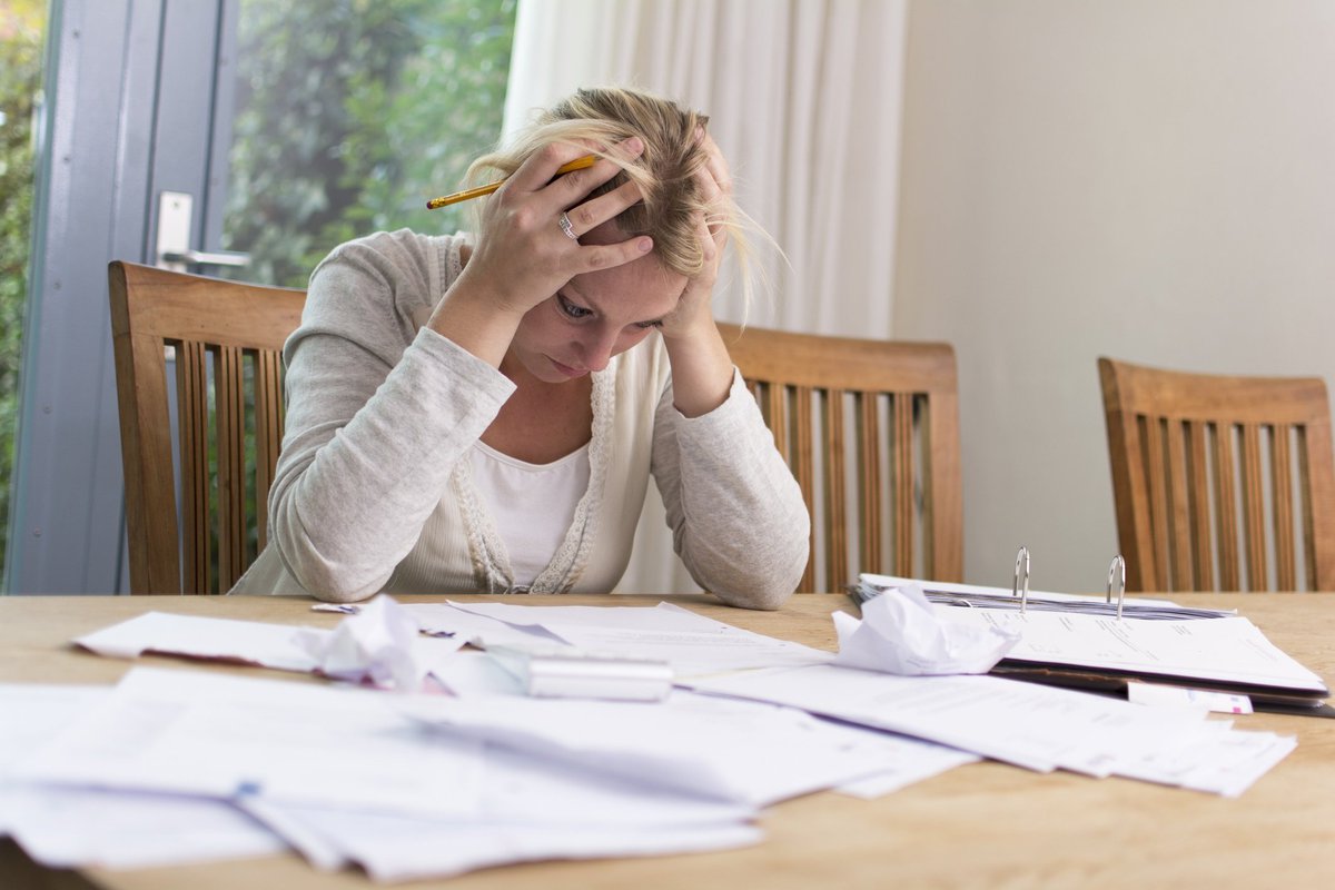 Frustrated woman with head in hands sitting at table