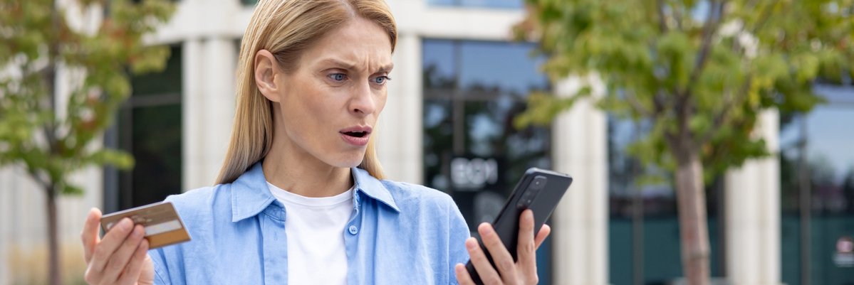 Person holding card and phone while looking confused and upset.