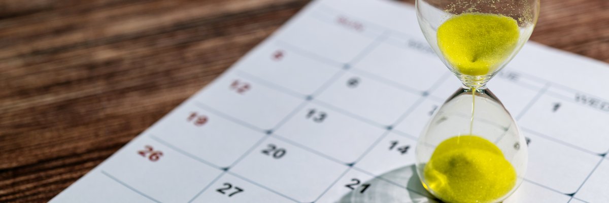 An hourglass on top of a calendar.