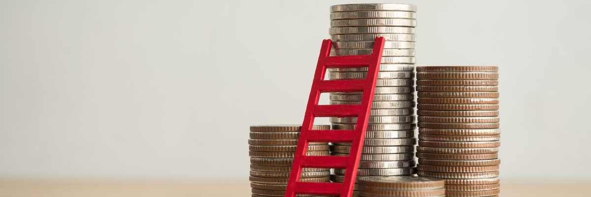 Stacks of coins in varying heights with a ladder leaning against the tallest one.
