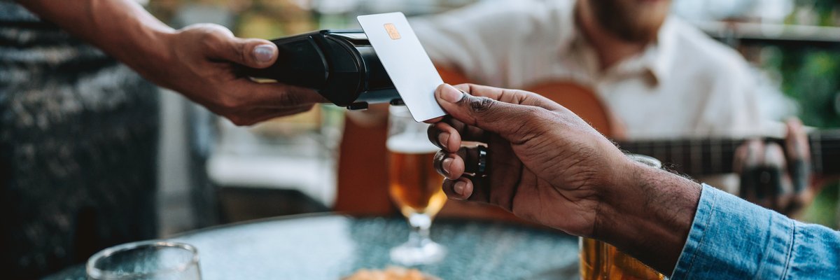 Person uses credit card to pay at outdoor restaurant.