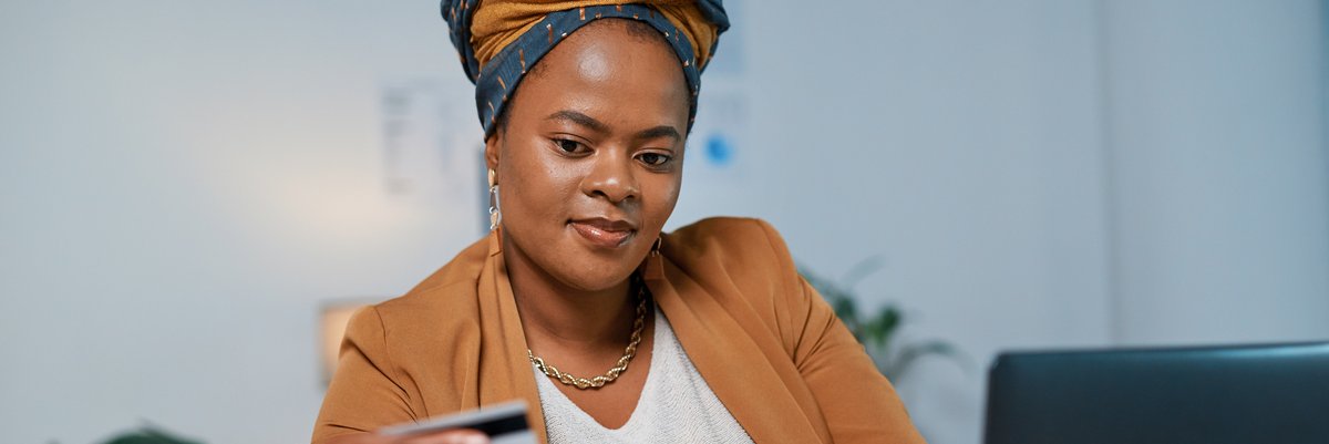 Person holds a credit card while using a laptop.
