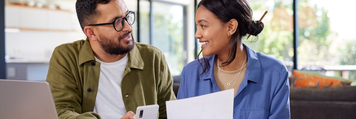 Happy couple looking at paperwork and cellphone.