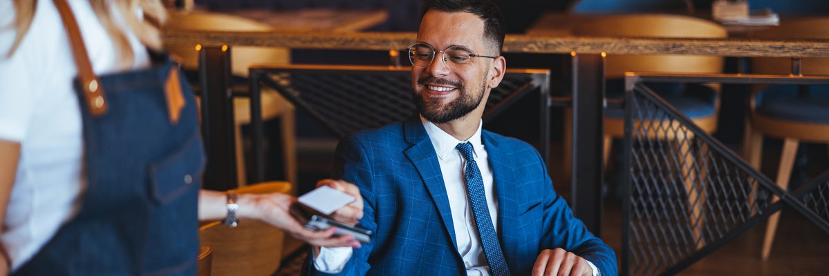 Man in suit uses a credit card to pay in a cafe.