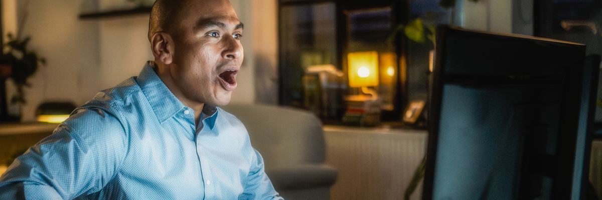 Man looking at computer screen with his mouth open in shock.
