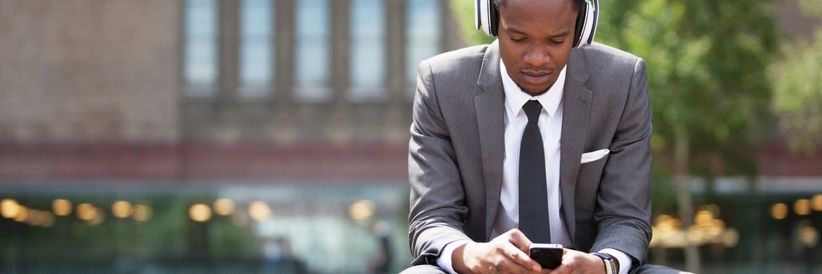 man in suit wearing headphones and looking at phone