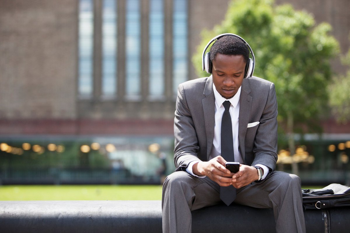 man in suit wearing headphones and looking at phone