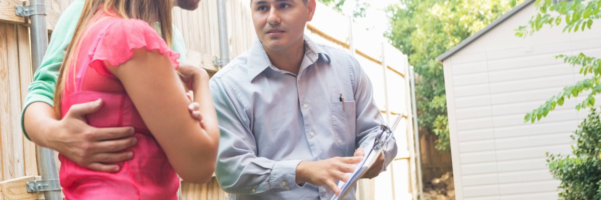 An air conditioner repairman uses a clipboard to explain the cost of repairs to the homeowners.