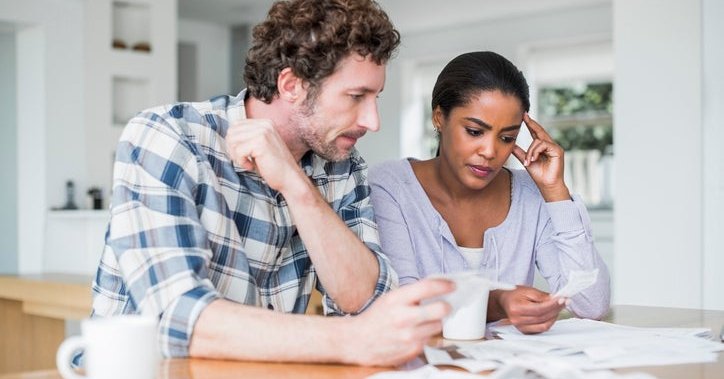 A couple looks at paperwork worriedly inside.