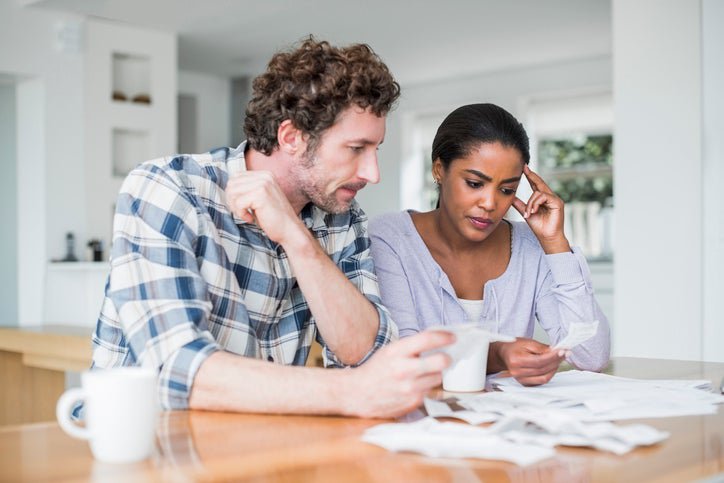 A couple looks at paperwork worriedly inside.