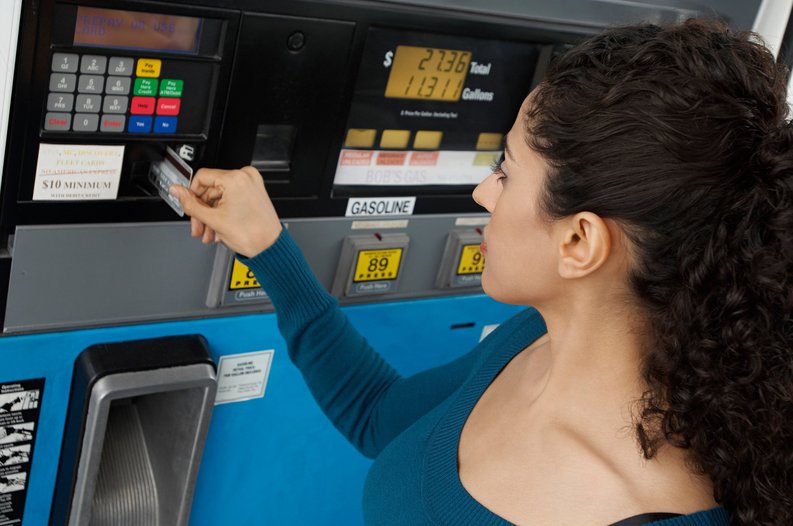 woman putting a credit card into a gas pump