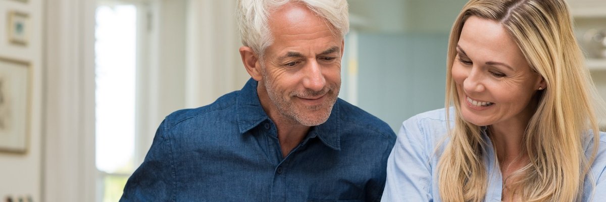Middle-aged man and woman looking at paperwork on table and smiling