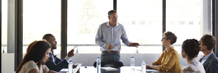 Businessman briefs his team at a conference table.