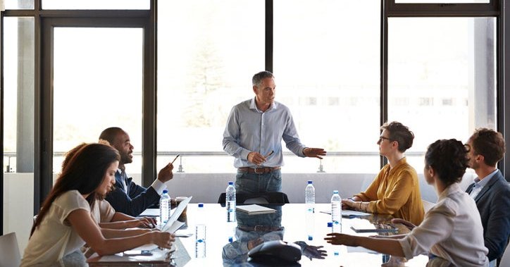 Businessman briefs his team at a conference table.
