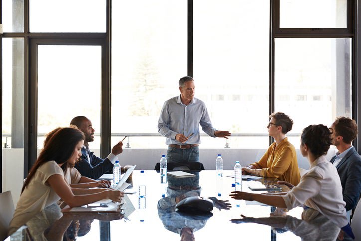 Businessman briefs his team at a conference table.
