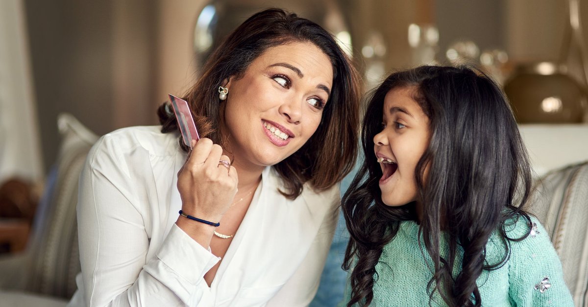 A parent teaches their child about credit cards through buying something online.