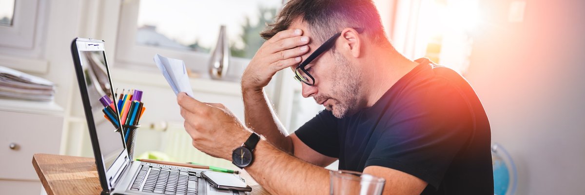 Stressed-out bespectacled man looking at document.