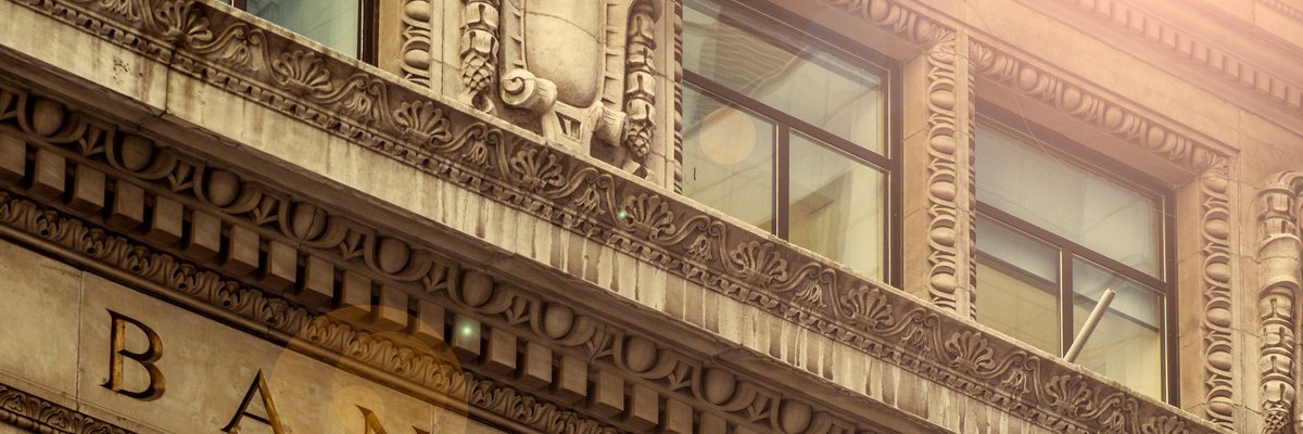 Sunlit facade of an archaic bank edifice.