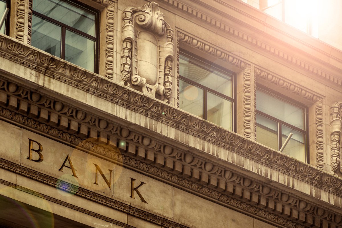 Sunlit facade of an archaic bank edifice.