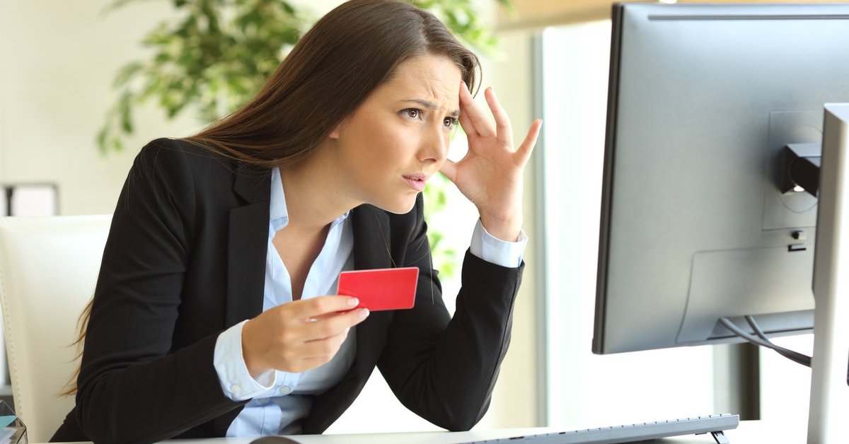 Frustrated woman holding credit card and looking at computer