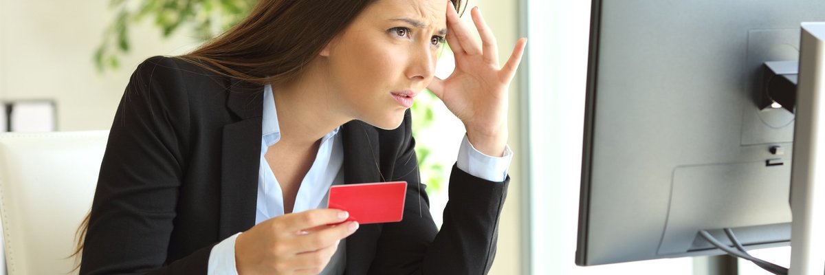 Frustrated woman holding credit card and looking at computer
