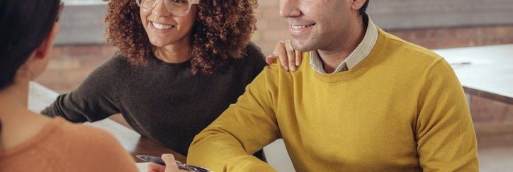 A couple smiles as they talk to a bank associate.