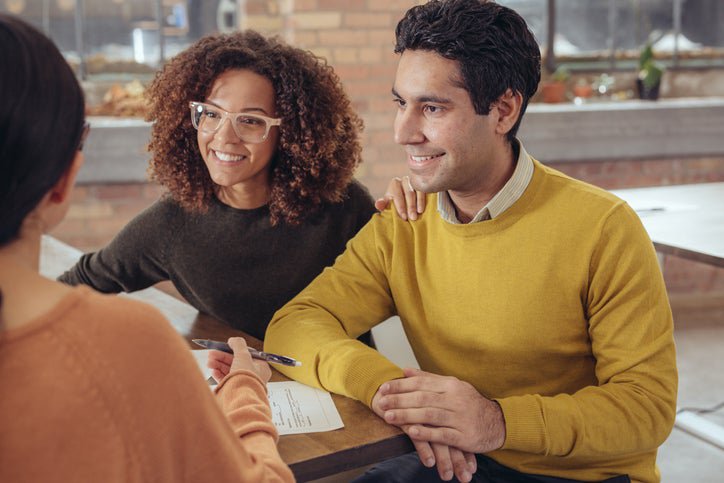 A couple smiles as they talk to a bank associate.