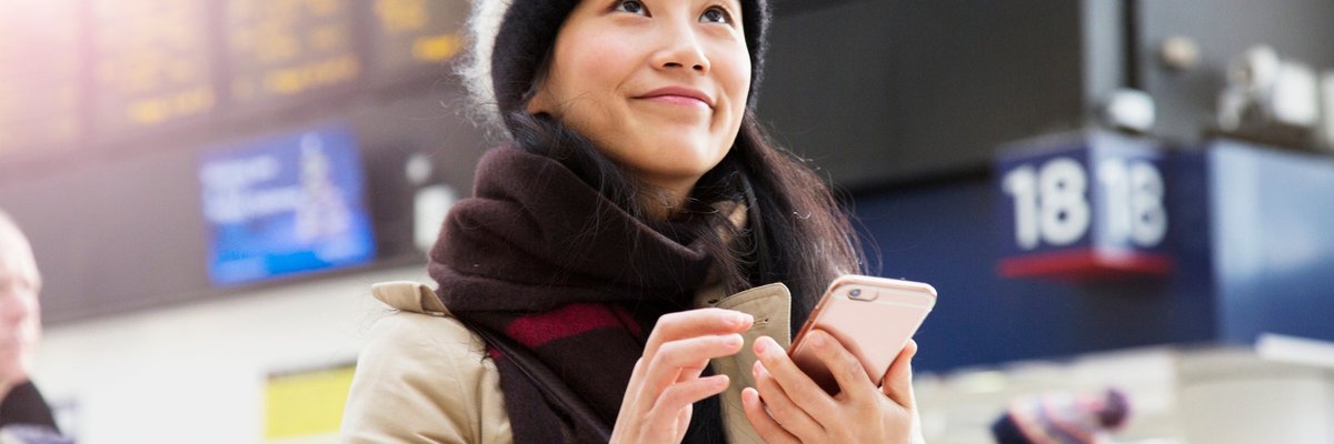 A visitor uses their smartphone as they wait for a train to arrive in a railroad station.