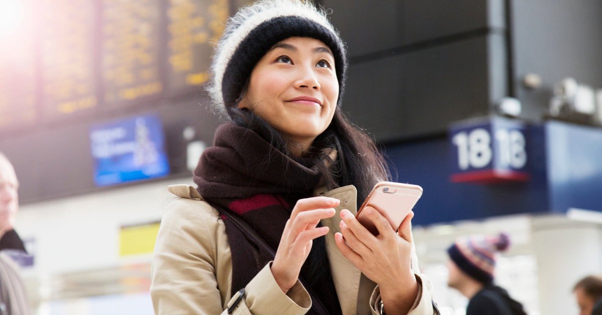 A visitor uses their smartphone as they wait for a train to arrive in a railroad station.