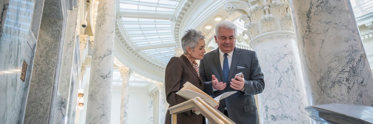 Two mature businesspeople discuss financial matters in a federal building.