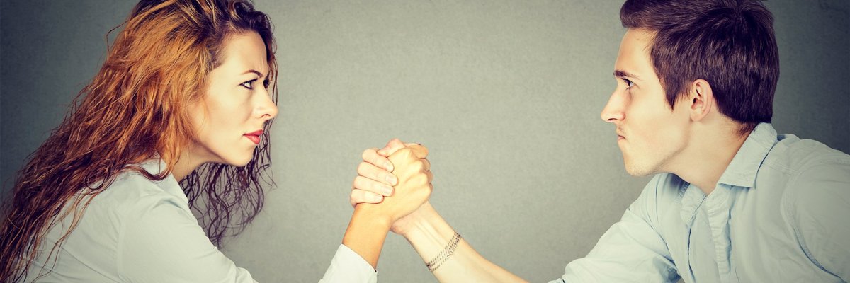 A man and woman arm wrestling.