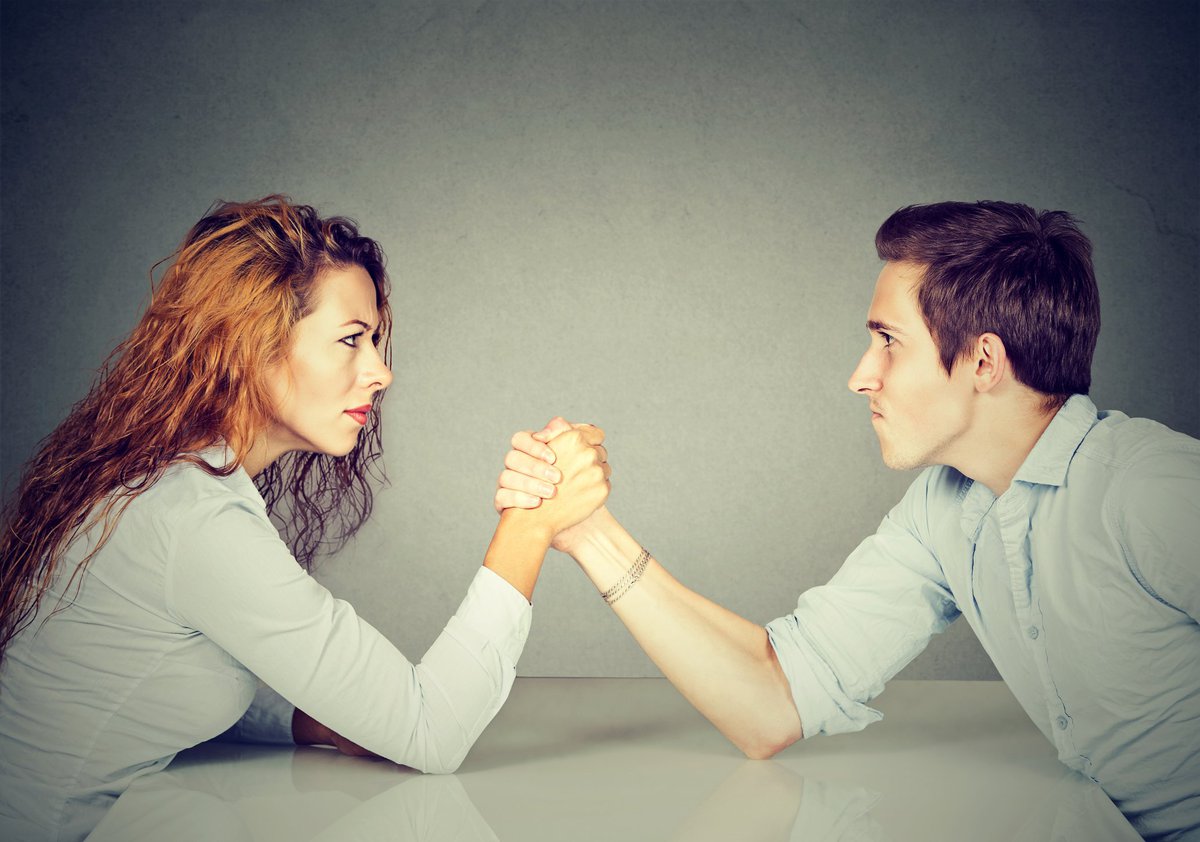 A man and woman arm wrestling.