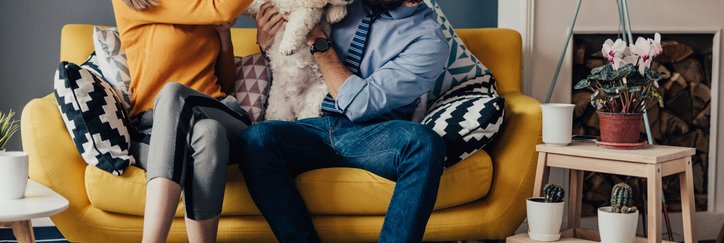 Laughing couple on couch with dog.