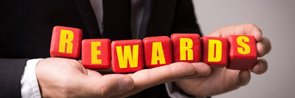 Man in suit holding letter blocks that spell out "rewards"