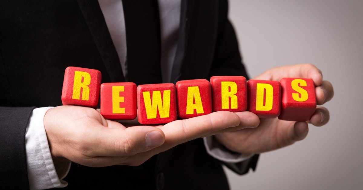 Man in suit holding letter blocks that spell out "rewards"